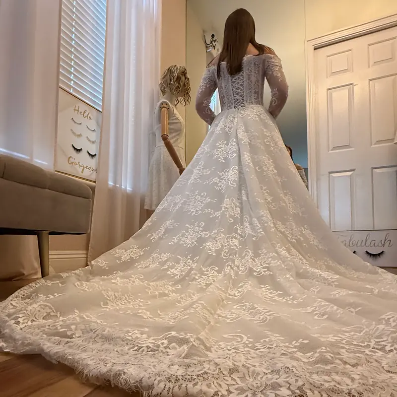 Bride in a lace ball gown with a full cathedral train laid out after alterations