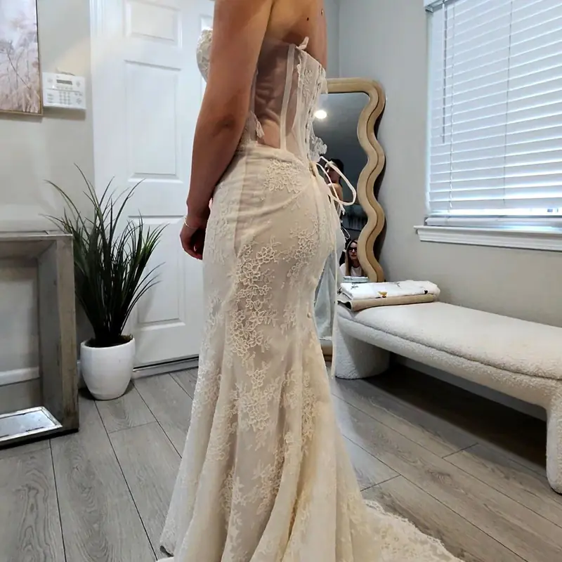 Fitted lace mermaid wedding gown with a corset back, seen from the side